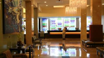 A hotel lobby with a reception desk, seating area, and a large abstract painting on the wall.