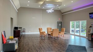 A spacious lobby with a modern ceiling design, a reception desk, and a seating area with striped chairs. - Motel 6 Rockford, IL (Rockford)