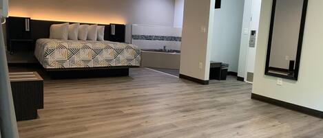 A modern hotel room with a large bed, a bathroom, and a mirror.