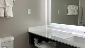 A modern bathroom with a toilet, sink, and mirror. There are towels hanging on the wall and a trash bin. - Motel 6 Rockford, IL (Rockford)