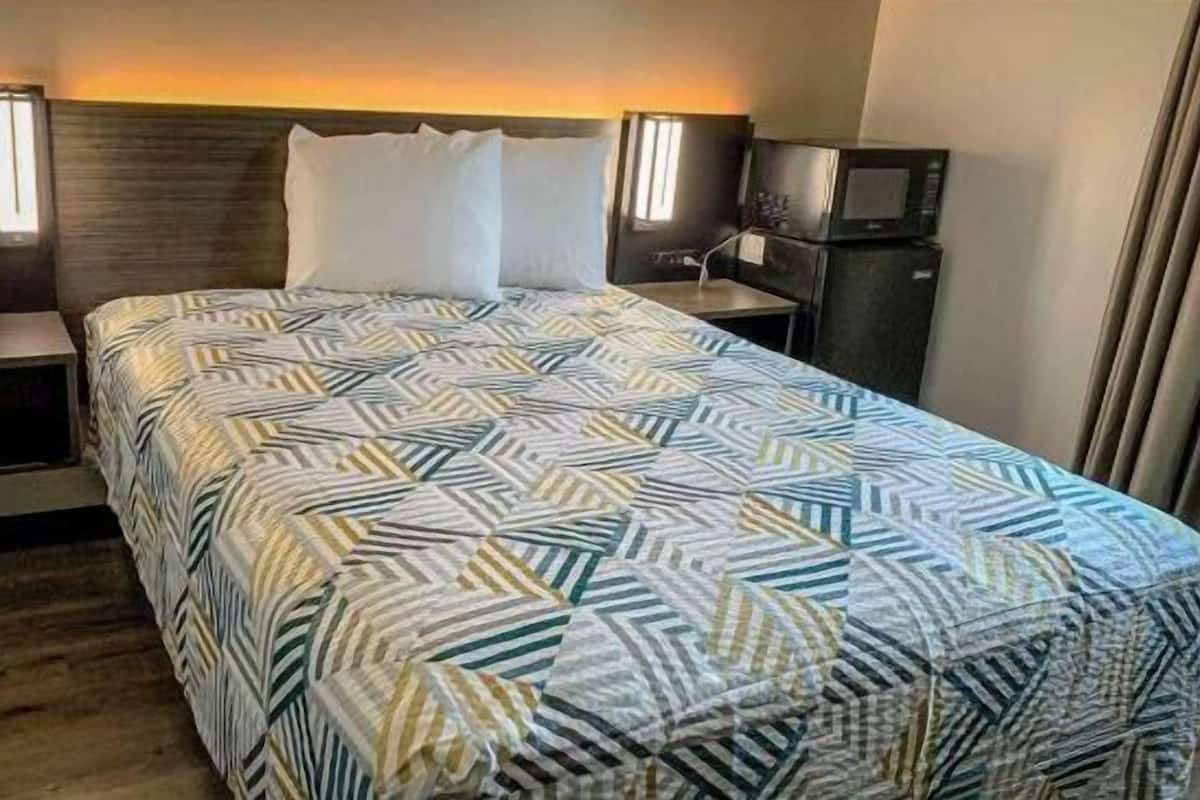 A hotel room with a bed, two bedside tables, a TV, and a telephone.