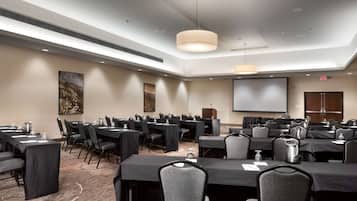 A conference room with multiple tables, chairs, and a projector screen.