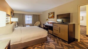 Una habitación de hotel con una cama grande, un escritorio con silla, un televisor y un armario.