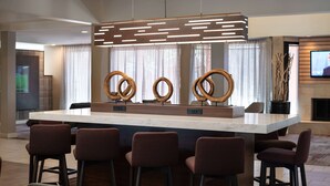 A modern kitchen with a central island, bar stools, and a contemporary pendant light. - Sonesta Select Phoenix Camelback (Phoenix)