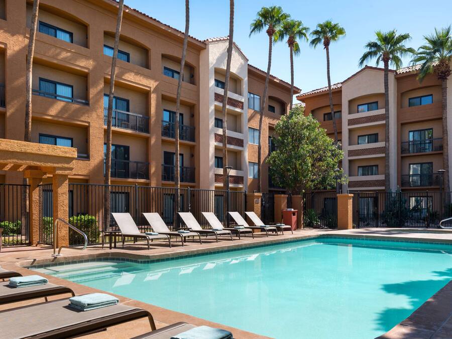 A hotel pool area with lounge chairs and a clear blue pool.