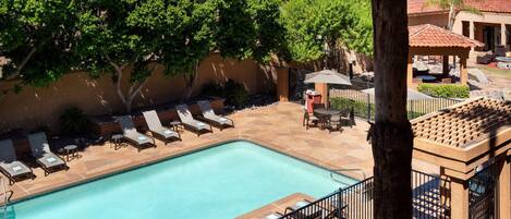 A swimming pool with lounge chairs and a covered seating area.