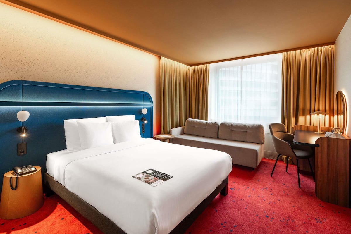 Una habitación de hotel con una cama grande, un sofá, un escritorio y una silla.