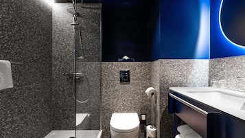 Un baño moderno con ducha de vidrio, inodoro y lavabo con espejo.