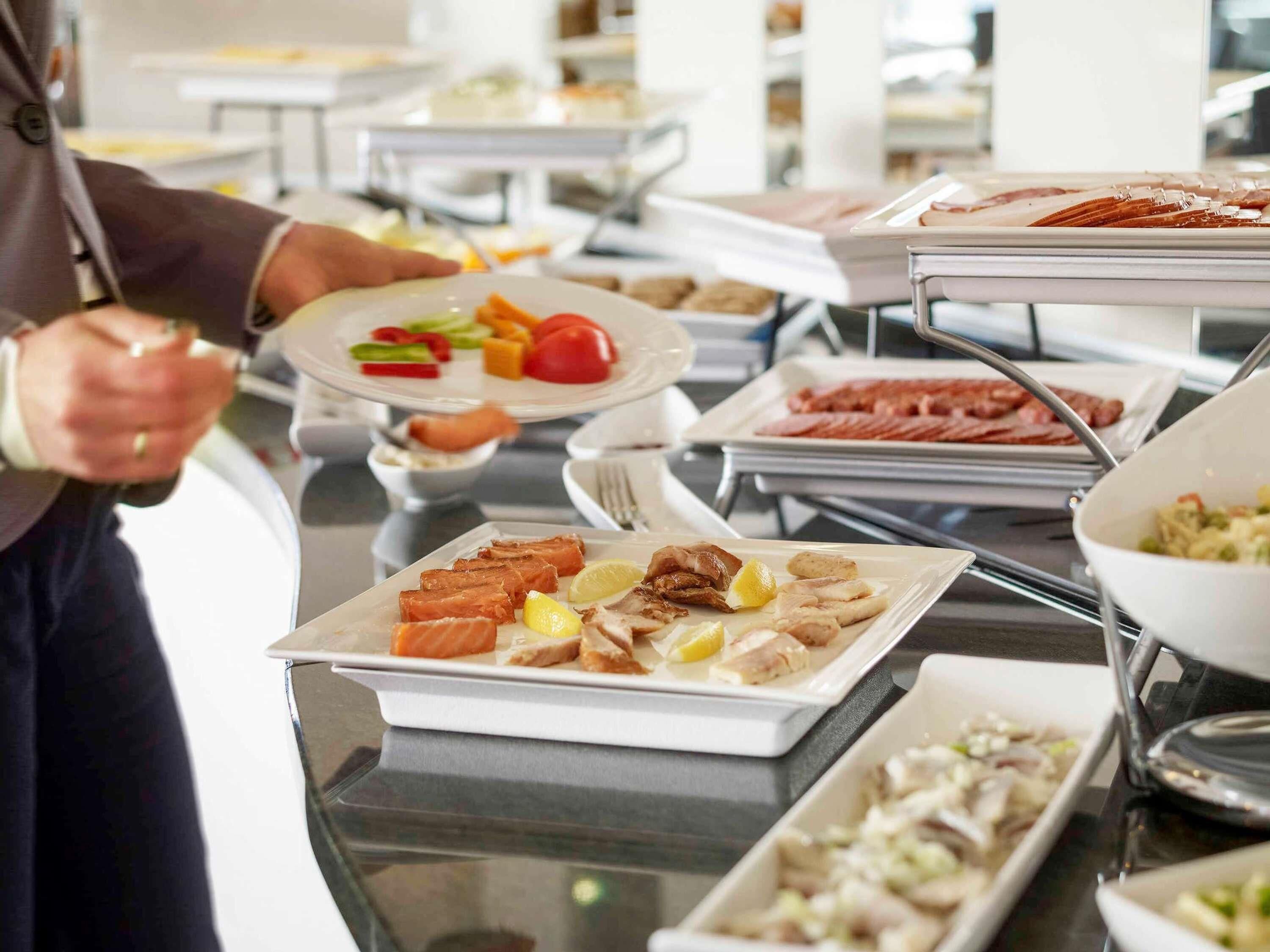 A buffet setup with various food items and a person serving.