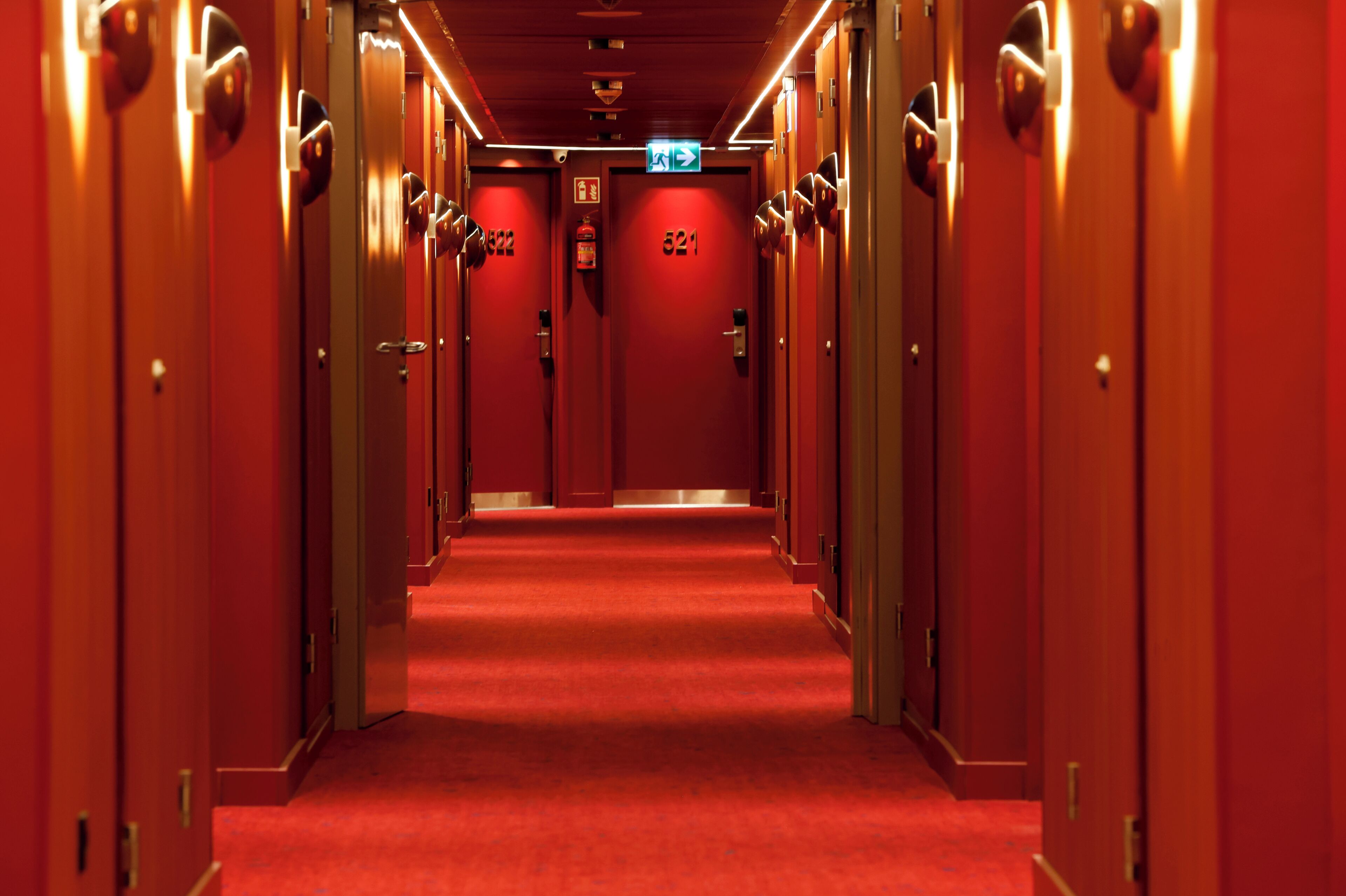 A hotel hallway with red carpet and doors numbered 522 and 521.