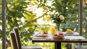 A breakfast table with plates of food, a glass of orange juice, and a vase with flowers. - Mercure Warszawa Centrum (Warsaw)