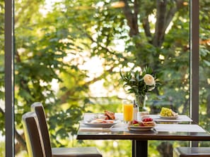 A breakfast table with plates of food, a glass of orange juice, and a vase with flowers. - Mercure Warszawa Centrum (Warsaw)