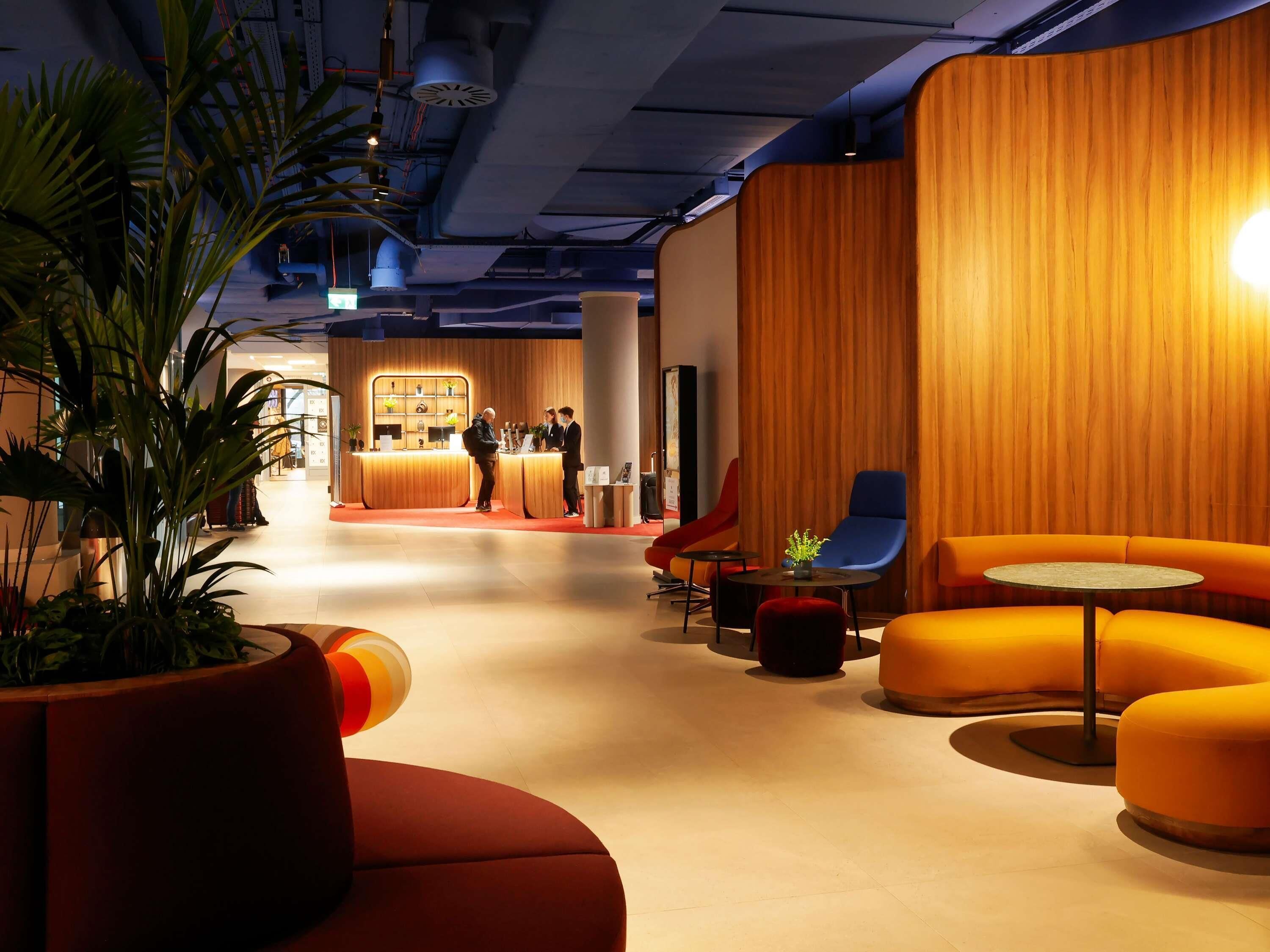 A modern lobby with a reception desk, seating area, and a plant.