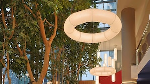 A modern indoor space with a red carpet, red chairs, a wooden wall, and a large tree. - Mercure Warszawa Centrum (Warsaw)