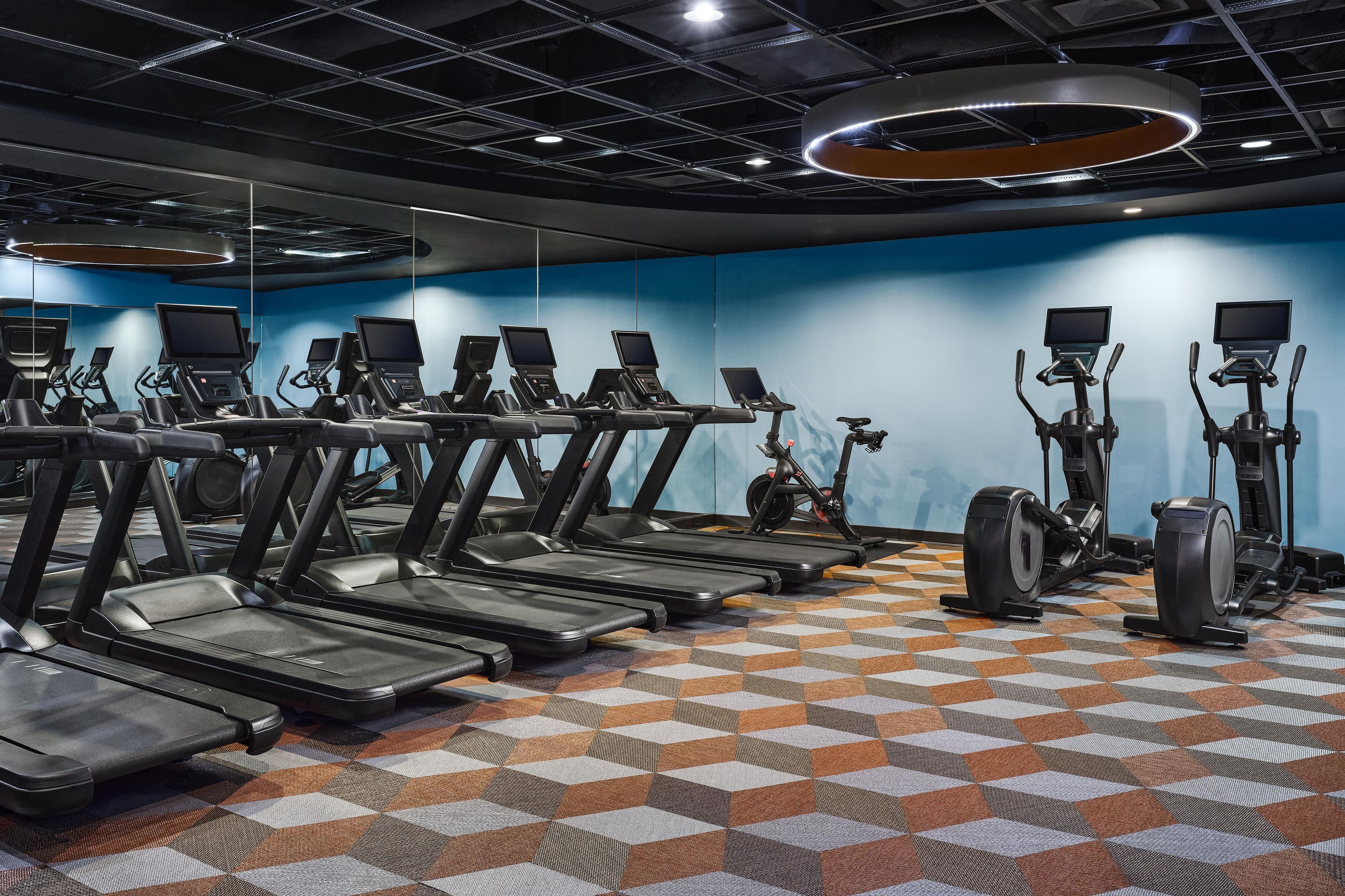 Un gimnasio con múltiples cintas de correr, bicicletas estáticas y elípticas.