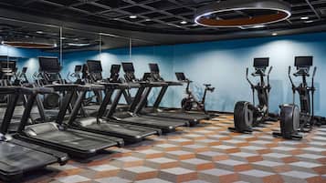 Un gimnasio con múltiples cintas de correr, bicicletas estáticas y elípticas.