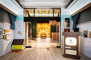 A modern interior with a reception desk, a pet area, and a bright, sunburst wall. - the Curtis Denver - a DoubleTree by Hilton Hotel (Denver)
