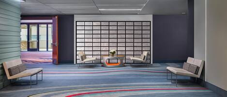 A modern lobby with a checkered floor pattern, two armchairs, a coffee table, and a large window with a view.