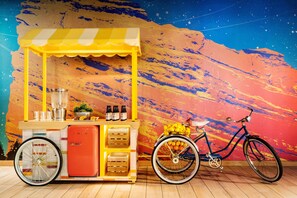A vibrant food cart with a yellow and white striped awning, a small refrigerator, and a bicycle parked beside it. - the Curtis Denver - a DoubleTree by Hilton Hotel (Denver)