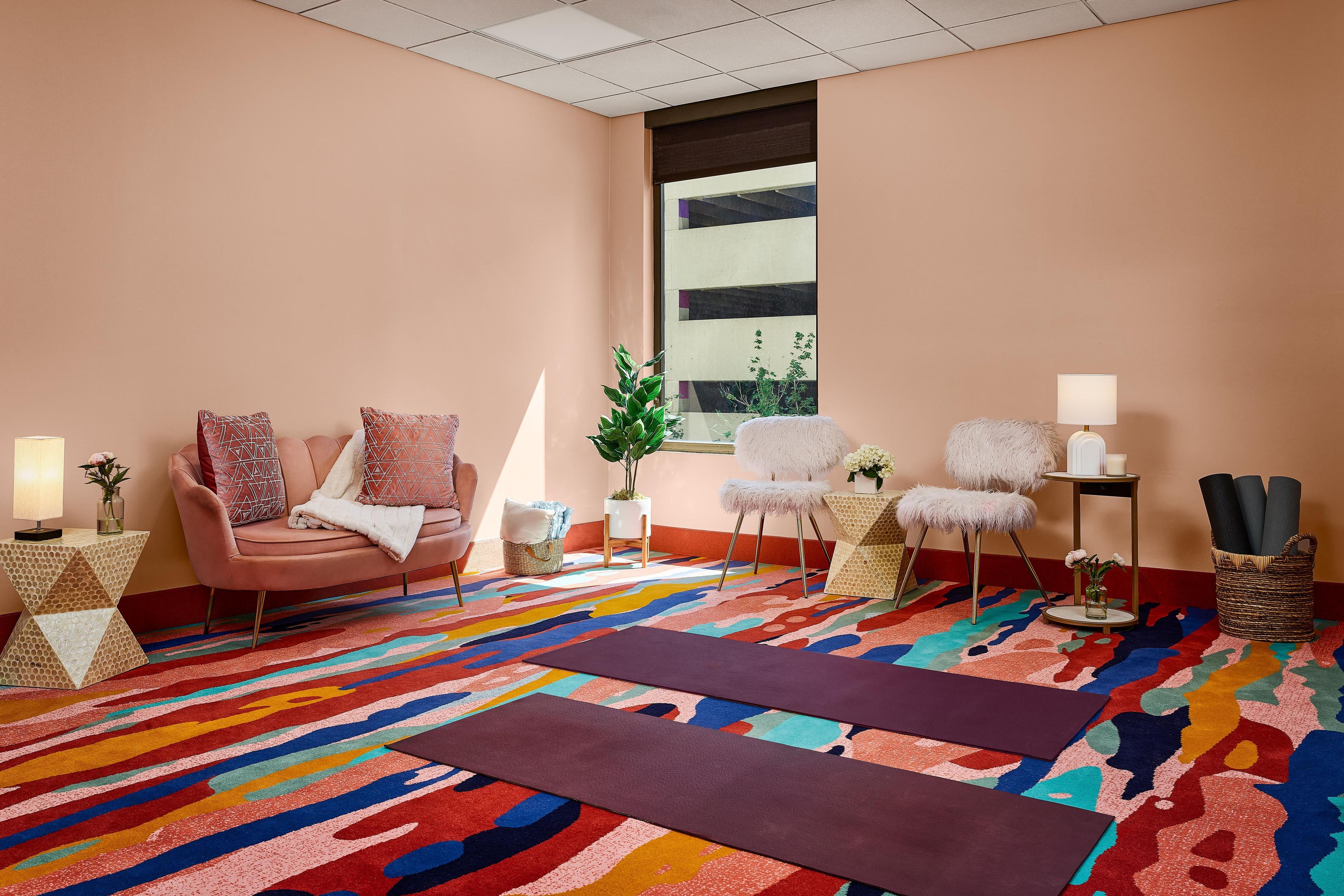 A room with a sofa, chairs, a patterned rug, and a window.