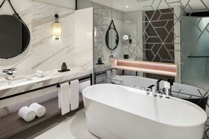 Un baño moderno con una bañera independiente, un espejo grande y una encimera de mármol.