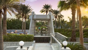 A bar area with a modern design, surrounded by palm trees and a clear sky. - Sheraton Jeddah Hotel - Saudi Brothers Commercial Company Branch (Jeddah)