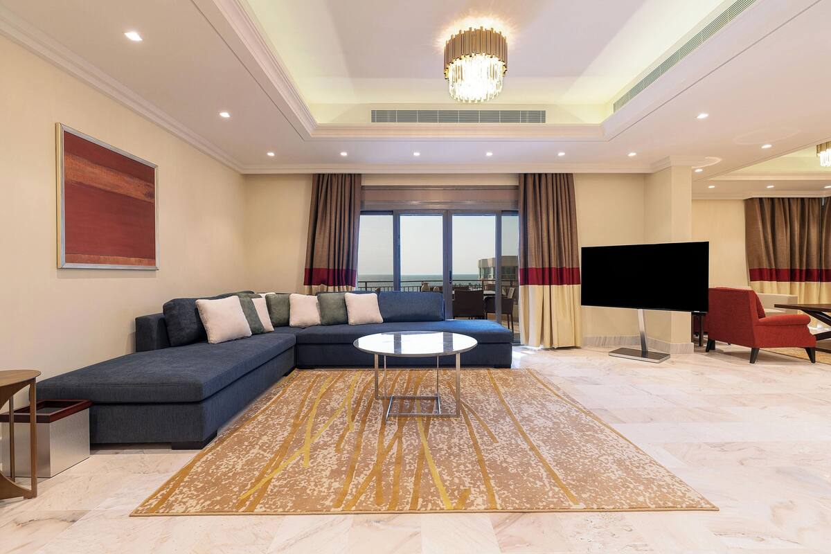 A modern living room with a sectional sofa, a round coffee table, and a flat-screen TV.