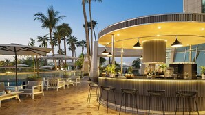 A bar area with a curved counter, bar stools, and a poolside seating arrangement with umbrellas. - Sheraton Jeddah Hotel - Saudi Brothers Commercial Company Branch (Jeddah)