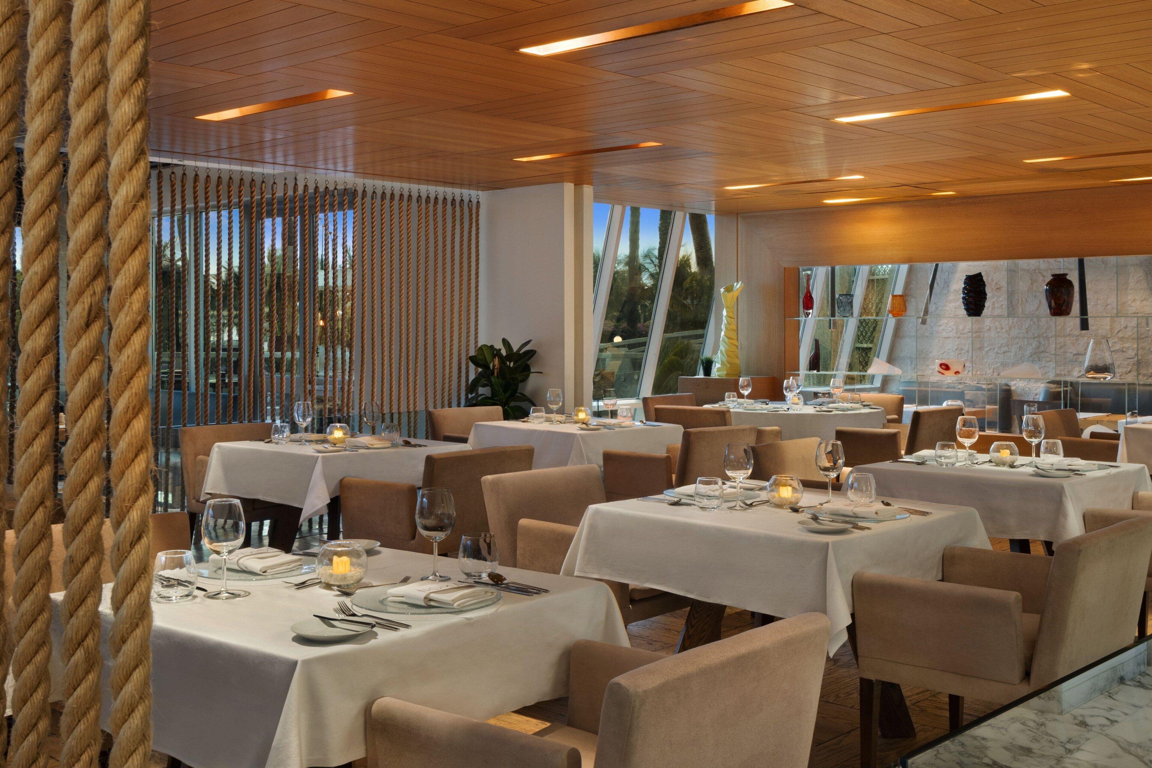 A restaurant with multiple tables set for dining, featuring white tablecloths and candle centerpieces.