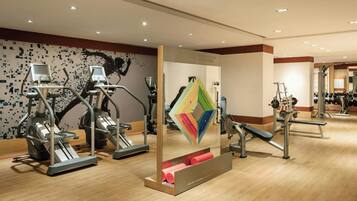 Un gimnasio con diversos equipos de ejercicio, como cintas de correr, elípticas y máquinas de pesas.