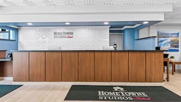 A reception area with a wooden reception desk, a digital payment terminal, and a reception desk mat with the property name.