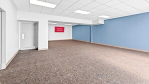 A spacious hallway with a carpeted floor, white walls, and a blue accent wall. A sign indicates free Wi-Fi is available in all rooms. - HomeTowne Studios by Red Roof & Conference Center Cortland (Cortland)