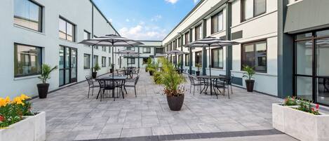 A courtyard with outdoor seating, potted plants, and a clear sky.