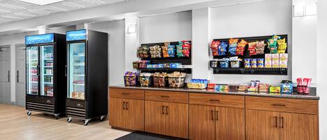 A snack bar with refrigerated beverage dispensers and a variety of packaged snacks.