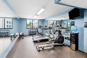 A gym with treadmills, elliptical machines, and free weights.