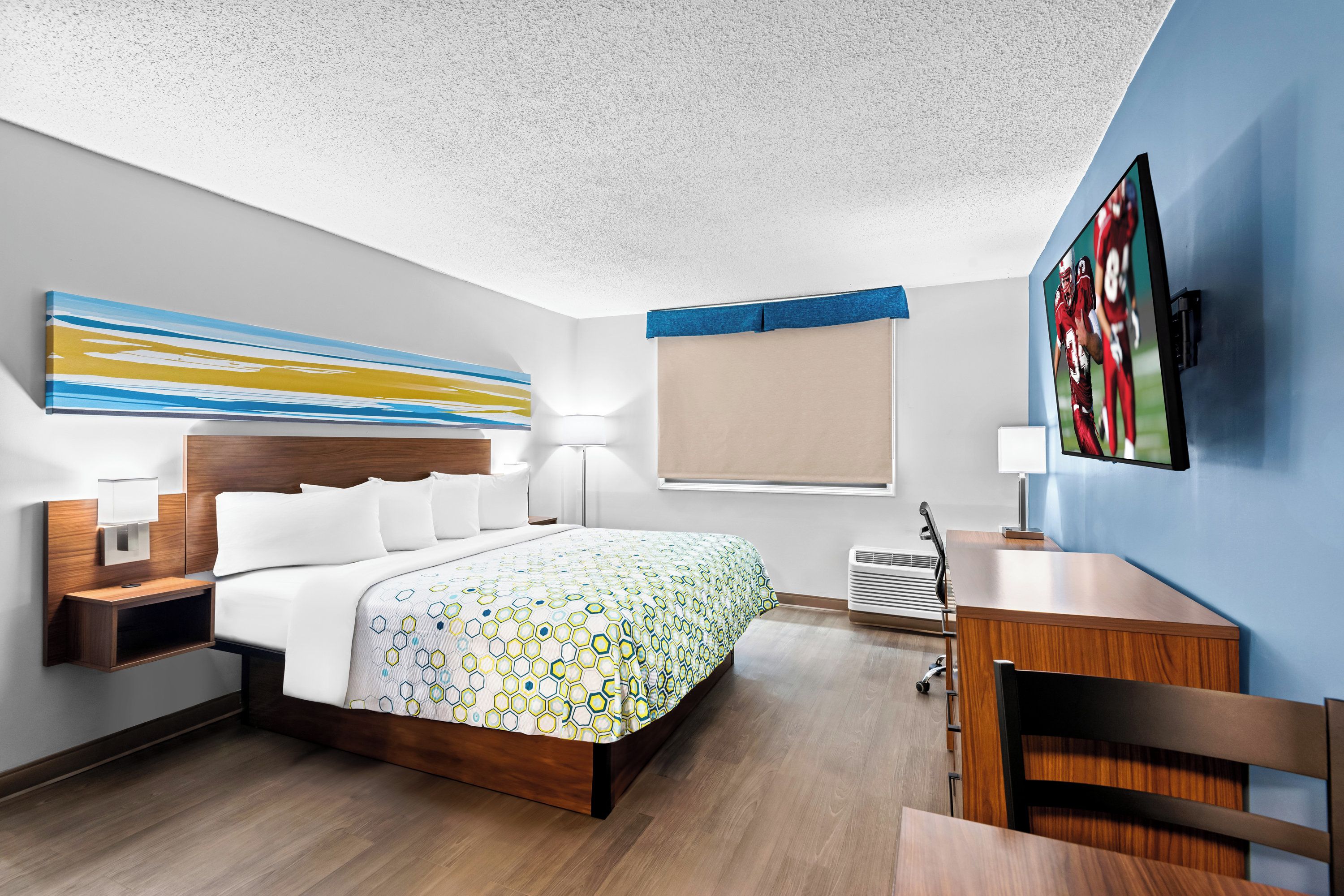 A hotel room with a bed, bedside tables, a desk, and a TV.