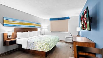A hotel room with a bed, bedside tables, a desk, and a TV.