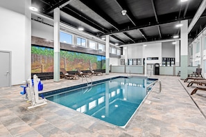 An indoor swimming pool with a clear view of the ceiling, a mural on the wall, and a lifeguard stand.
