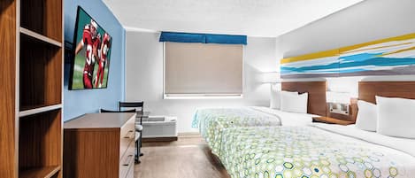 Een hotelkamer met een bed, een bureau, een stoel, een raam en een schilderij aan de muur.