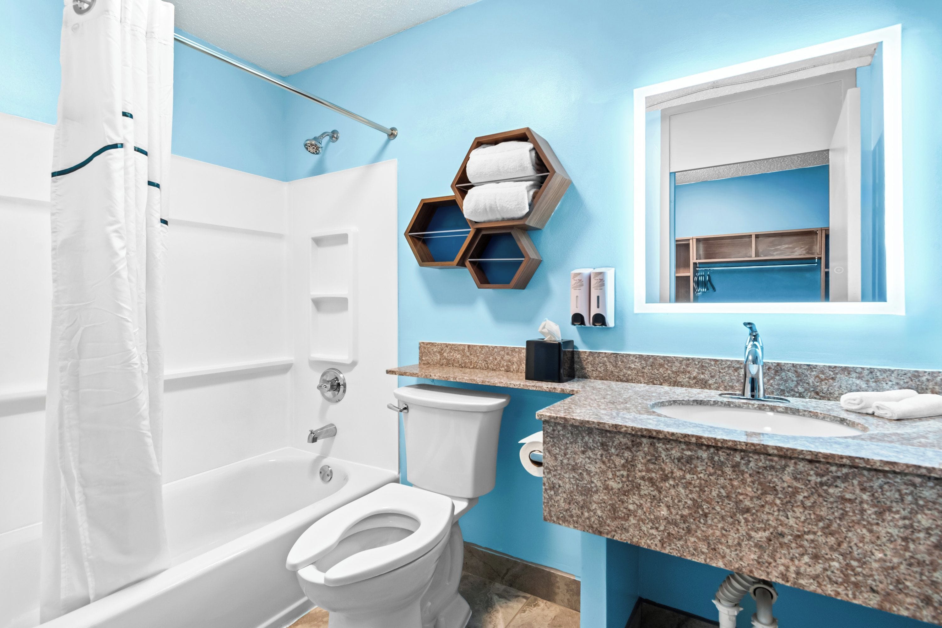 A bathroom with a bathtub, toilet, and sink. There is a shower curtain, a towel rack, and a mirror above the sink.
