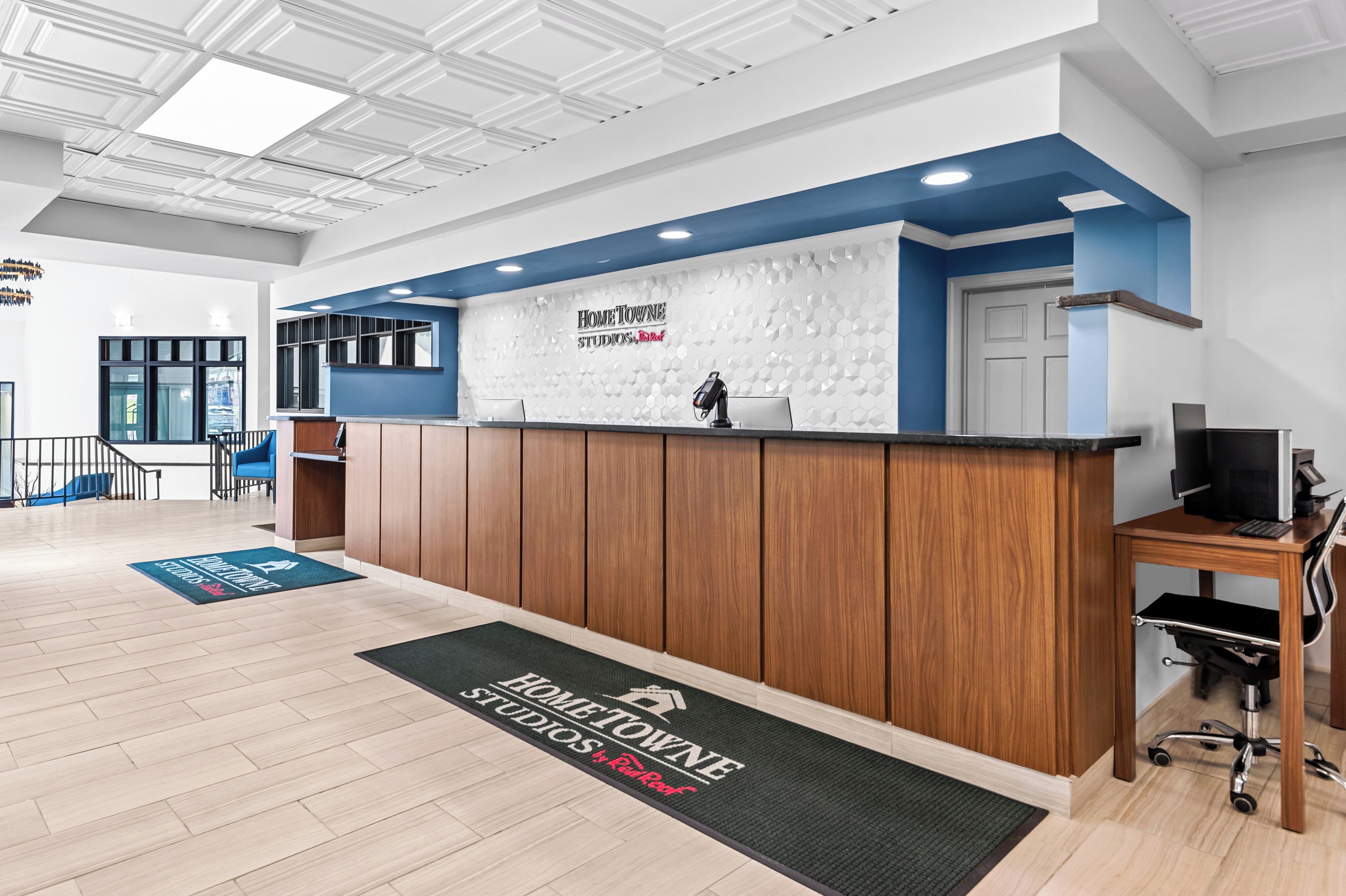 Un área de recepción con un escritorio de madera, una pared azul decorativa y un letrero que dice "HomeTowne Studios, Inc.".