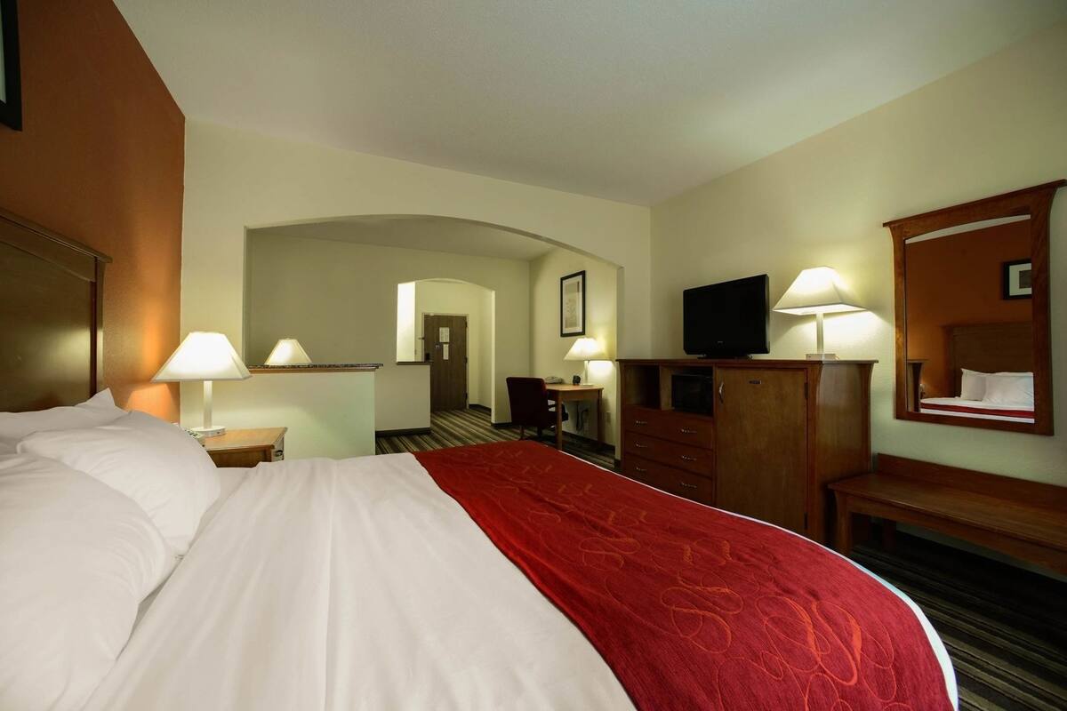 Een hotelkamer met een groot bed, een bureau, een televisie en een spiegel.