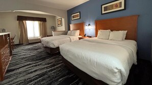 A hotel room with two beds, a desk, and a chair.