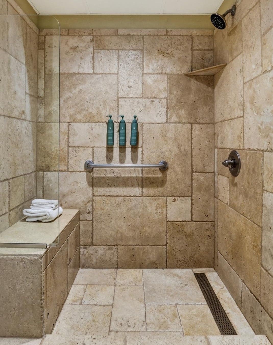 A shower area with a tiled wall, a towel rack, and a shelf.
