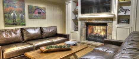 A living room with a leather sofa, a wooden coffee table, and a fireplace.