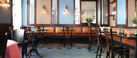 A restaurant interior with a checkered floor, wooden furniture, and decorative wall panels.