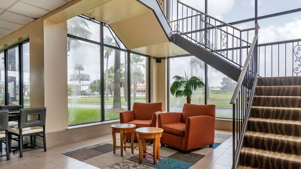 A spacious lobby with a staircase, large windows, and a seating area with two armchairs and a small table.