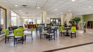 A spacious indoor area with multiple tables and chairs, large windows, and a central counter.