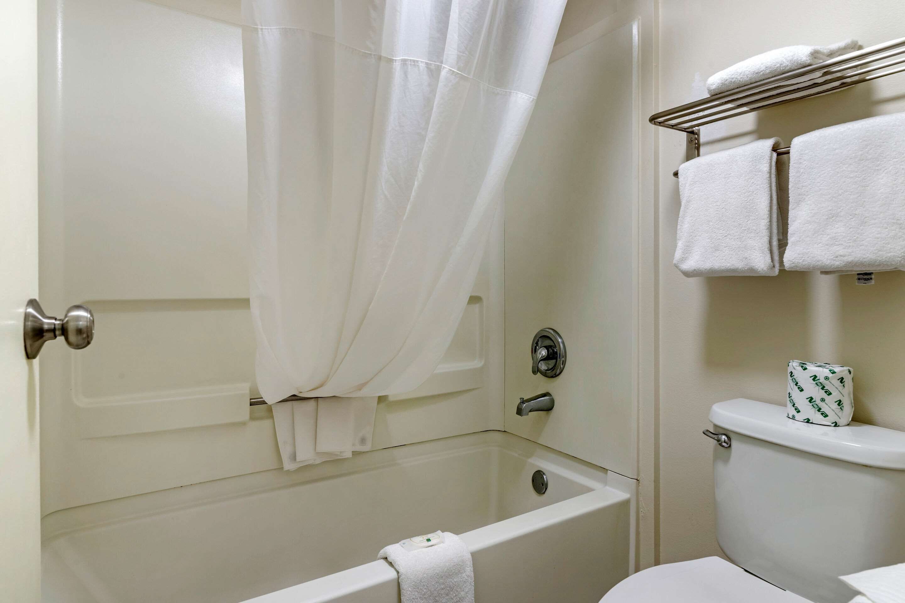 A bathroom with a bathtub, toilet, and a towel rack.