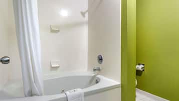 A bathroom with a bathtub, a shower curtain, a toilet, and a green wall.